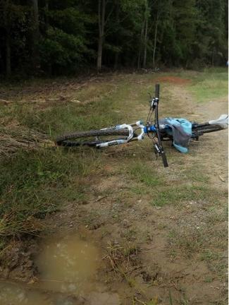A bicycle on an unkept and muddy forest biking path