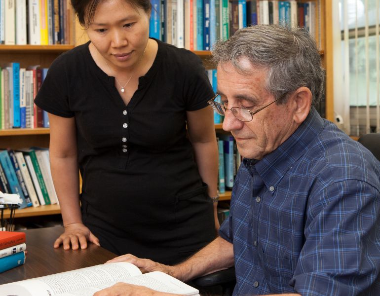 016516.jpg University of Florida Institute of Food and Agricultural Sciences researchers Hyeyoung Kim, left, and Ronald Ward, professor emeritus in agricultural marketing reading a textbook in an office.