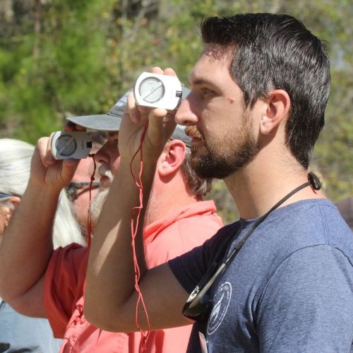 Line of participants using equipment to measure trees