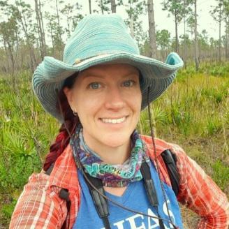 Shelly Johnson standing in forest smiling into camera