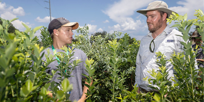 Student and instructor discussing crop production during a hands-on agricultural learning experience.