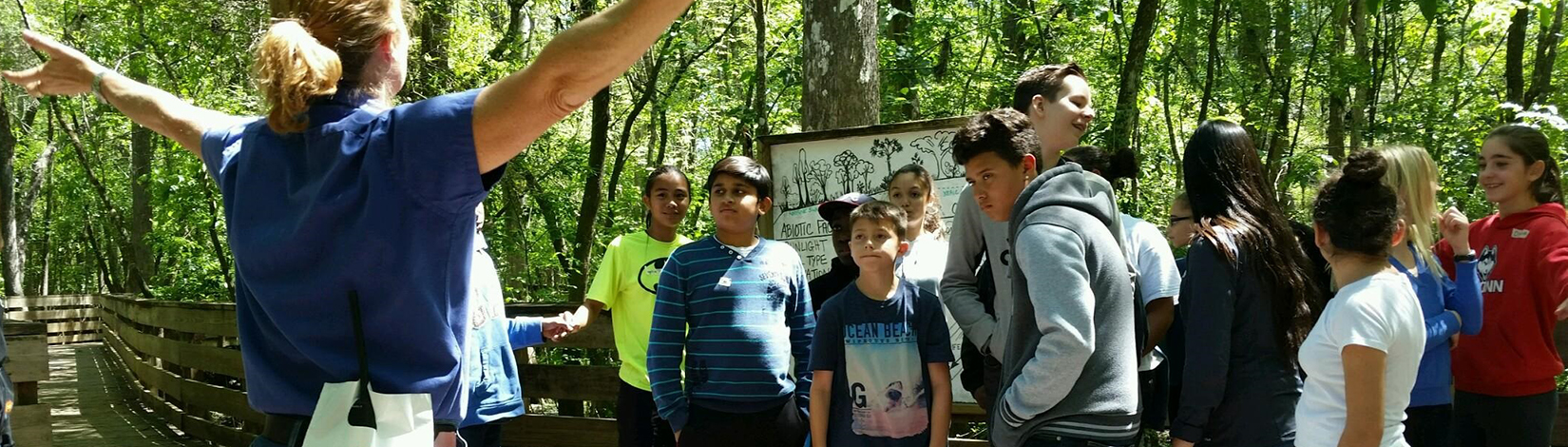 Middle school-age students with teacher in a forest