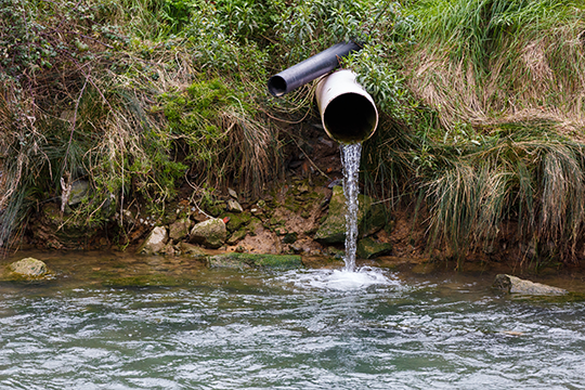 a large and small pipe both pumping water into a stream
