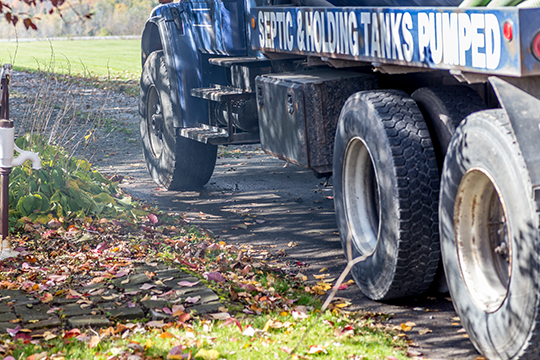 close up of a large truck that uses a hose to vacuum wastewater from a septic tank